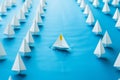 In a sea of white, a lone blue paper boat leads