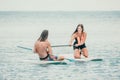 Sea woman and man on sup. Silhouette of happy young woman and man, surfing on SUP board, confident paddling through