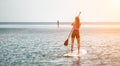 Sea woman and man on sup. Silhouette of happy young woman and man, surfing on SUP board, confident paddling through