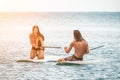 Sea woman and man on sup. Silhouette of happy young woman and man, surfing on SUP board, confident paddling through