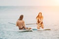 Sea woman and man on sup. Silhouette of happy young woman and man, surfing on SUP board, confident paddling through