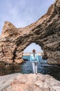 Sea woman rocks grotto. A woman in a blue jacket stands on a rock above a cliff above the sea and looks at the raging Royalty Free Stock Photo