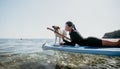 Sea woman sup. Silhouette of happy positive young woman with her dog, surfing on SUP board through calm water surface Royalty Free Stock Photo