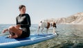 Sea woman sup. Silhouette of happy positive young woman with her dog, surfing on SUP board through calm water surface Royalty Free Stock Photo