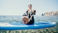 Sea woman sup. Silhouette of happy positive young woman with her dog, surfing on SUP board through calm water surface Royalty Free Stock Photo