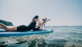 Sea woman sup. Silhouette of happy positive young woman with her dog, surfing on SUP board through calm water surface Royalty Free Stock Photo