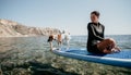 Sea woman sup. Silhouette of happy positive young woman with her dog, surfing on SUP board through calm water surface Royalty Free Stock Photo