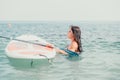 Sea woman sup. Silhouette of happy young woman in pink bikini, surfing on SUP board, confident paddling through water Royalty Free Stock Photo