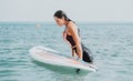 Sea woman sup. Silhouette of happy young woman in pink bikini, surfing on SUP board, confident paddling through water Royalty Free Stock Photo