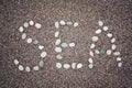 'Sea' word on the sand. Written with pebbles. Aged photo. Royalty Free Stock Photo