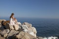 At the sea young woman sitting on rock Royalty Free Stock Photo