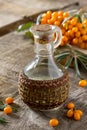 Seabuckthorn berries branch of sea buckthorn and oil on a vintage wooden background