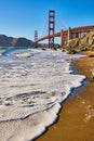 Seafoam on wet sandy beach with Golden Gate Bridge in background