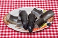 Seafood background. Close-up of fresh cleaned pieces of raw european eel fish on a porcelain plate on a red checkered tablecloth. Royalty Free Stock Photo