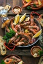 Seafood dinner. Grilled tiger prawns in grilling pan with fresh lemon, garlic, bread over wooden background, top view.