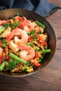 Seafood dish with rice, prawns, chicken meat and vegetables in a small paella pan on a dark rustic wooden table, selected focus Royalty Free Stock Photo