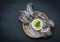 Seafood fresh squid on ice basket with lemon parsley on dark background