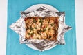 Fish baked in a foil with tomatoes, entirely with onion rings, red and green peppers, chili peppers, greens, cheese, mushrooms Royalty Free Stock Photo