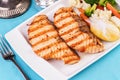 Grilled seafood. Salmon fish steak with greens, broccoli, cauliflower, carrots, cucumber, lemon and chili. Royalty Free Stock Photo