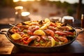 Seafood paella with a glass of wine on the table, set against a Mediterranean sea view at sunset