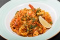 Seafood paella with rice, tomato sauce, langoustine, mussels, squid, shrimp and greens on plate on black wooden background. Royalty Free Stock Photo