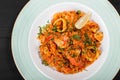 Seafood paella with rice, tomato sauce, langoustine, mussels, squid, shrimp and greens on plate Royalty Free Stock Photo