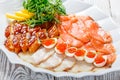 Seafood platter with salmon slice, smoke sturgeon, quail eggs with red caviar, slices fish fillet with arugula on wood background Royalty Free Stock Photo