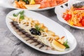 Seafood platter with smoked mackerel slice, fried potatoes, slices fish fillet, decorated with onion over rustic background