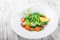 Seafood salad with mussels, squids, octopus, arugula, lettuce and cherry tomatoes on wooden background close up