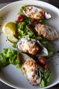 Seafood. Shellfish mussels. Baked mussels with cheese, cilantro and lemon in shells on cast iron black plate. Royalty Free Stock Photo