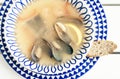 Seafood soup with mussels, prawns and fish in white bowl with blue ornament on the wooden table in restaurant, top view Royalty Free Stock Photo