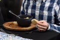 Man eating seafood spicy soup with potatoes, shrimps, herbs and fish from a picad closeup in a pan served with toast