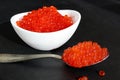 Red caviar in a white plate with a spoon lies on a black background Royalty Free Stock Photo