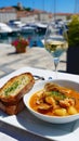Seafood stew and garlic bread with white wine by harbor on sunny day Royalty Free Stock Photo