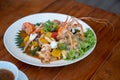 Seafood Thai mixxed together between boiled shrimp, crab, squid and colourful vegetable in dish on wood table in restaurant