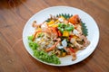 Seafood Thai mixxed together between boiled shrimp, crab, squid and colourful vegetable in dish on wood table in restaurant