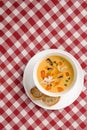 Tomato soup with mussel and pasta in a bowl on plaid tablecloth. Italian cioppino soup with bread. Top view copy space
