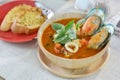 Seafood tomato soup served with garlic bread on cutting board an Royalty Free Stock Photo