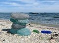 Seaglass stack on beach sand with seascape background. Beachcombing, beach walk. Harmony and balance concept