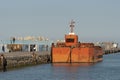 Seagoing orange coloured barge berthed in Heraklion port, Crete Greece.