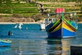 Seagull flying away from a Maltese fishing boat (luzzu) at Marsaxlokk fishing village in Malta