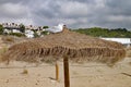 Seagull perches on top of a straw sun umbrella on a sandy beach Royalty Free Stock Photo