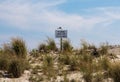 Seagull standing on a please keep off the dunes sign