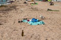 Seagulls, blankets, towels, shoes, vacationers and an empty bottle on the beach in the village of Zaliznyi Port in the Kherson