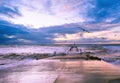 Seagulls flying over large waves crushing on small jetty. Royalty Free Stock Photo