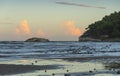 Seagulls flying between waves breaking on sandy shoreline after sunset. Royalty Free Stock Photo