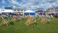 Empty deck chairs with fabric blowing in the wind on a green at a festival