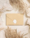 Sealed envelope near beige travertine stones and dried pampas grass top view, greeting mockup Royalty Free Stock Photo