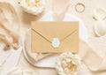 Sealed envelope near cream roses and petals, ring and silk ribbons top view, wedding mockup Royalty Free Stock Photo