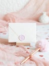 Sealed envelope near pink decorations, hearts and tulle on white table close up, mockup